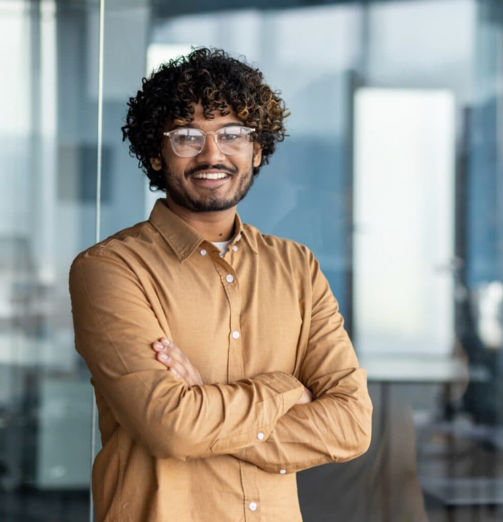 Smiling man with curly hair and glasses in an office.