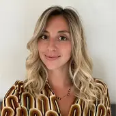 A woman with wavy blonde hair and a patterned top.
