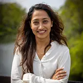 Smiling woman with long dark hair wearing a white shirt.