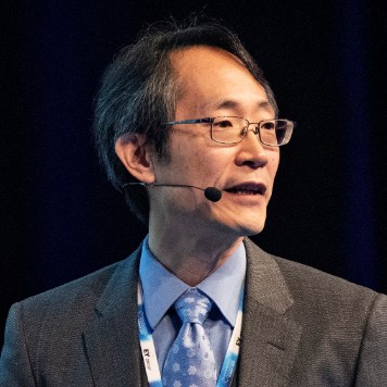 A man with glasses speaking into a headset microphone