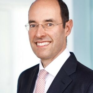 Smiling man in a suit and glasses professional headshot.