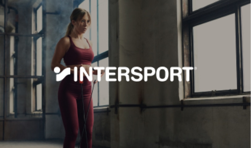 Woman in maroon activewear in a gym with Intersport logo.