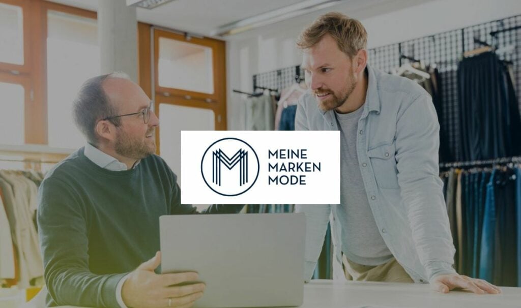 Two men collaborating at a laptop in a clothing store.