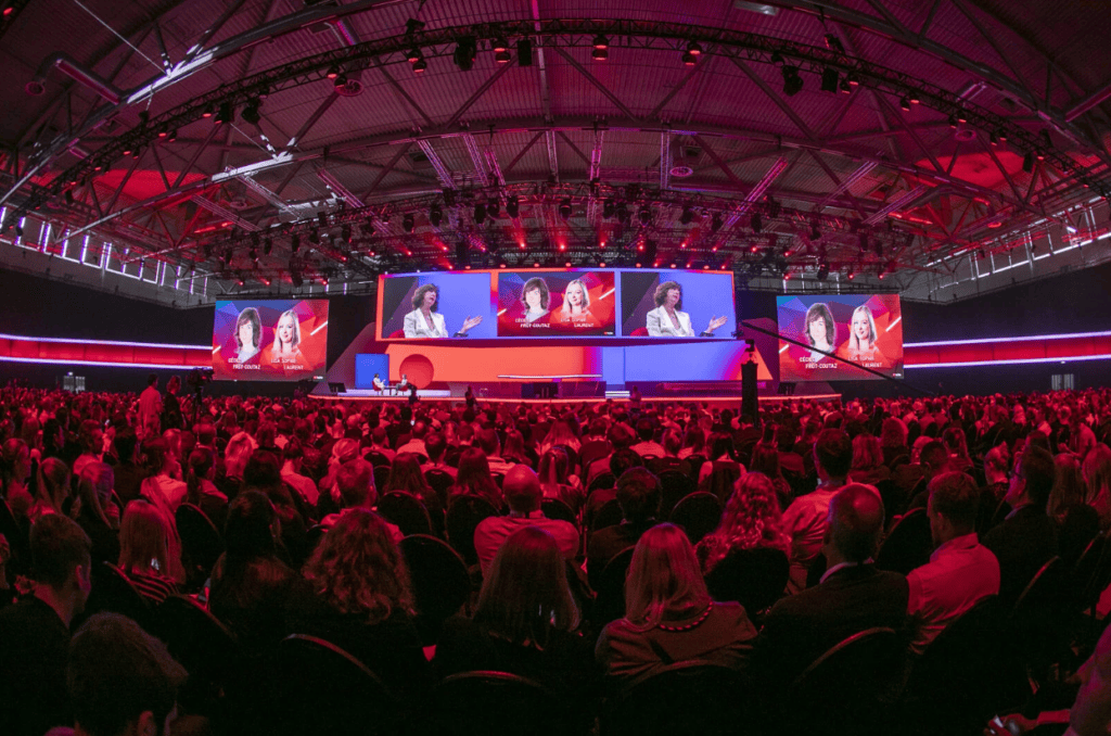 Large audience seated in a hall for a keynote presentation.