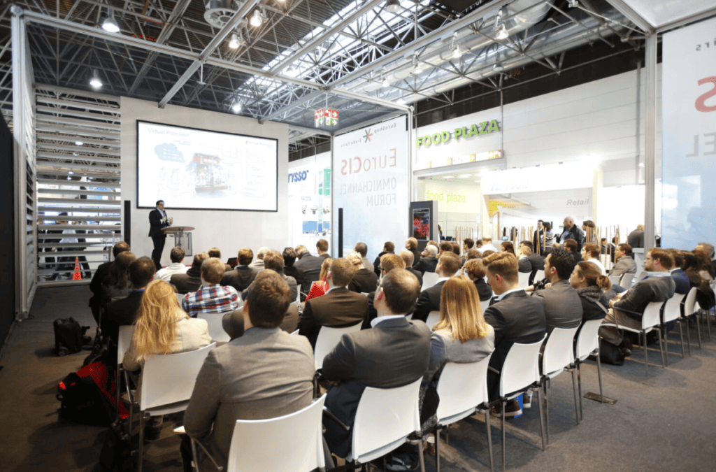 Speaker presenting to a seated audience at an industry forum.