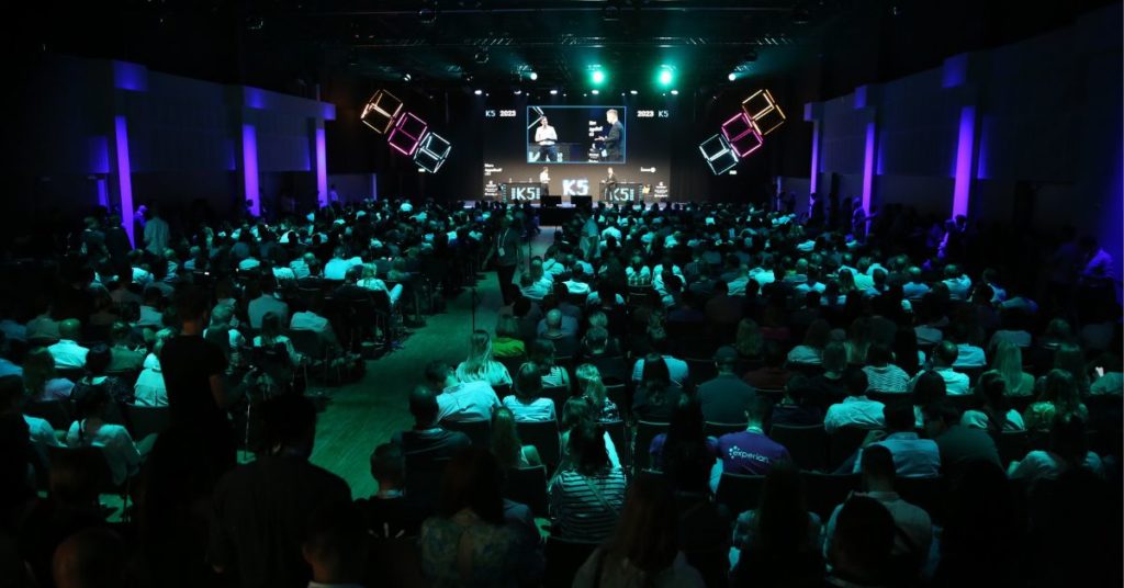 Large audience watching a presentation on a stage.
