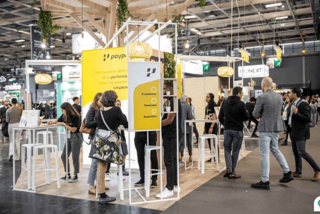 People networking at a payp trade show exhibition booth.