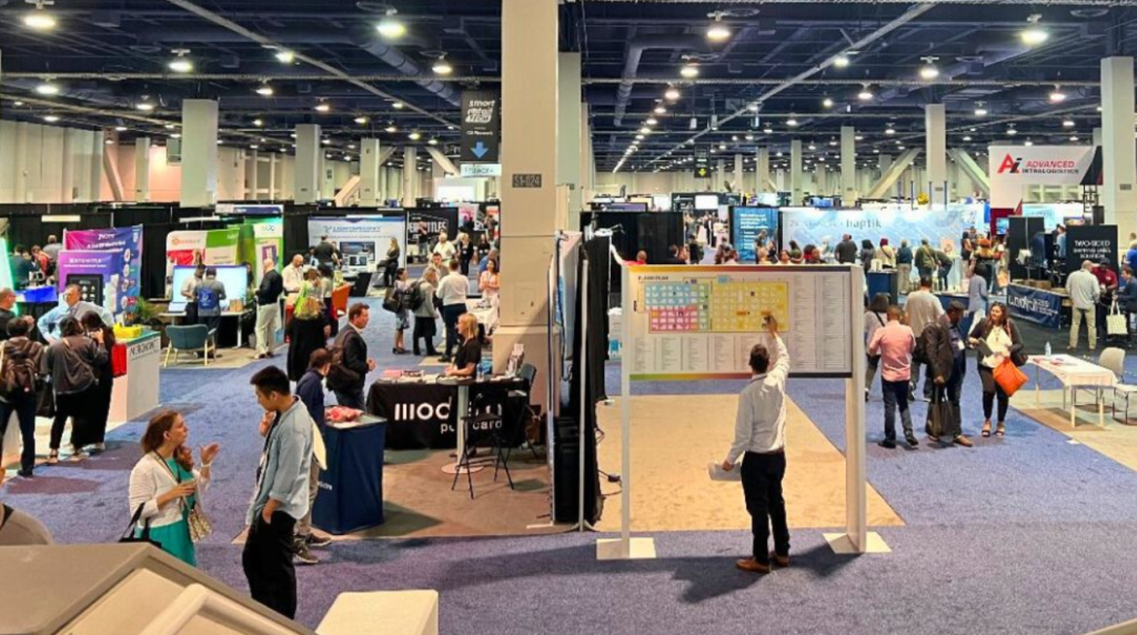 A busy trade show floor with people visiting various booths.