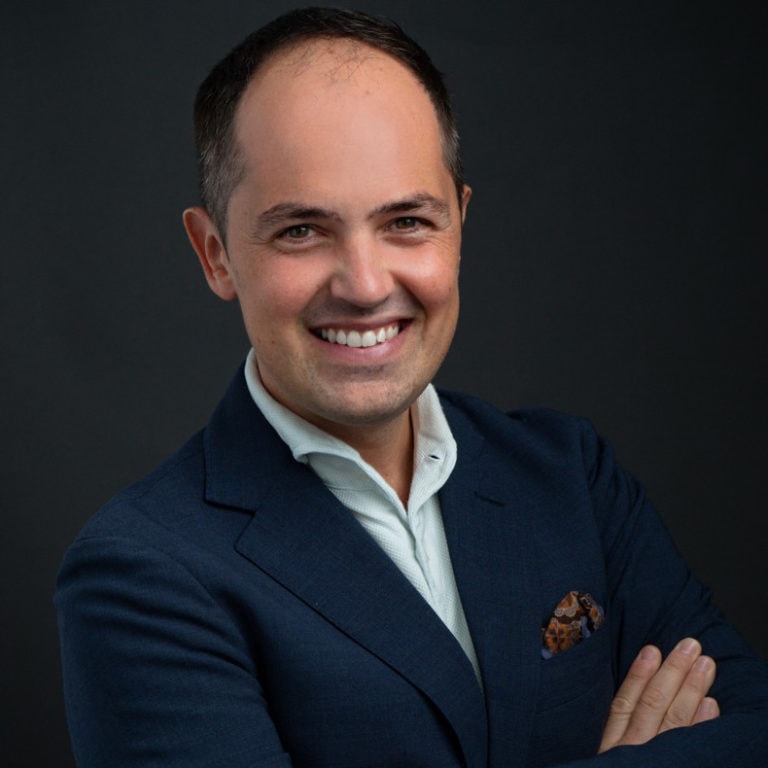 Smiling man in a blue blazer and white shirt.