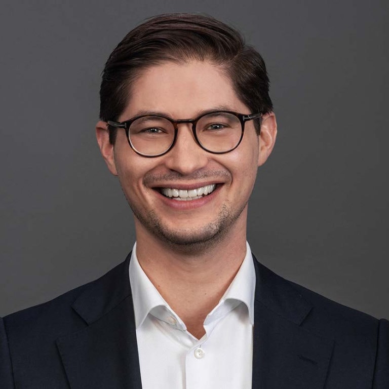 Professional headshot of a smiling man wearing glasses.