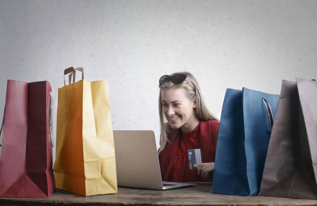 A woman happily online shopping with her credit card.