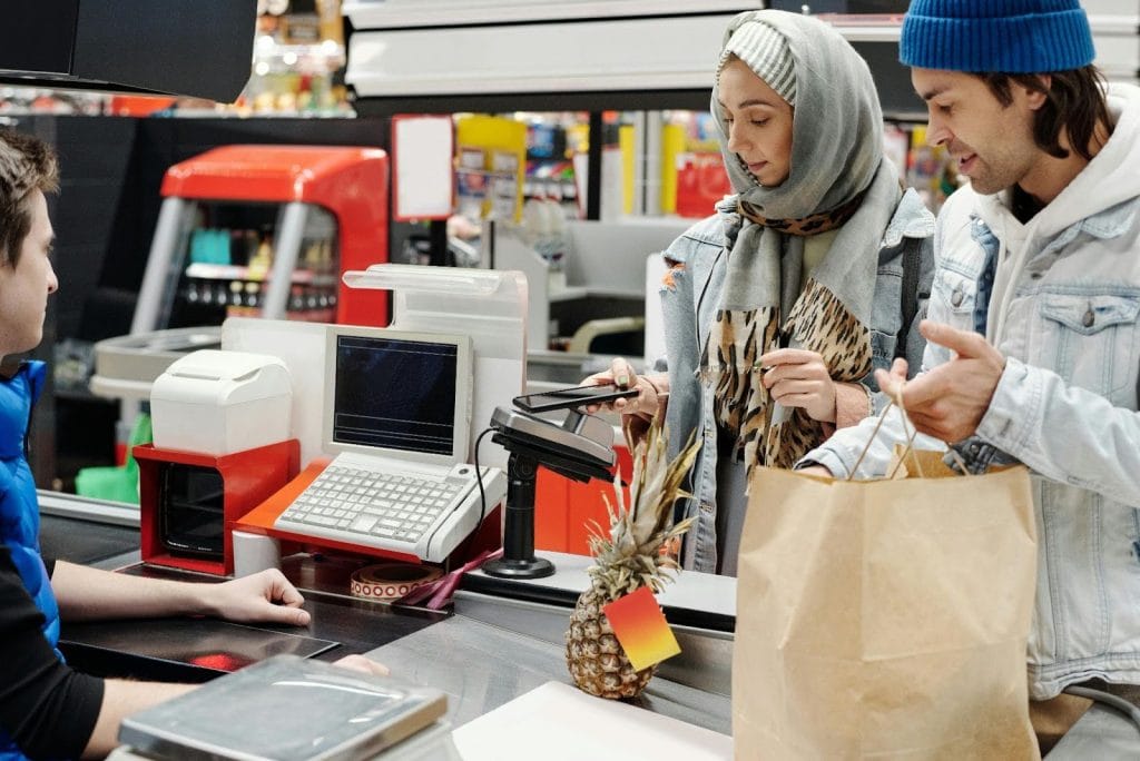 Woman pays with smartphone at a grocery store checkout.