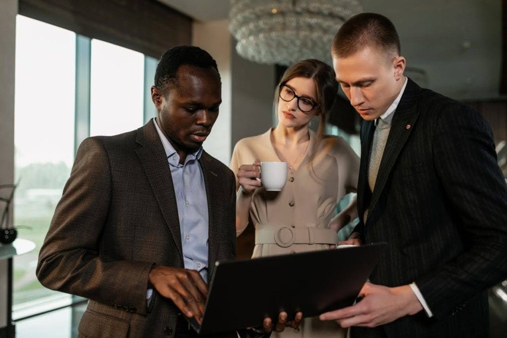 Three professionals collaboratively looking at a laptop screen