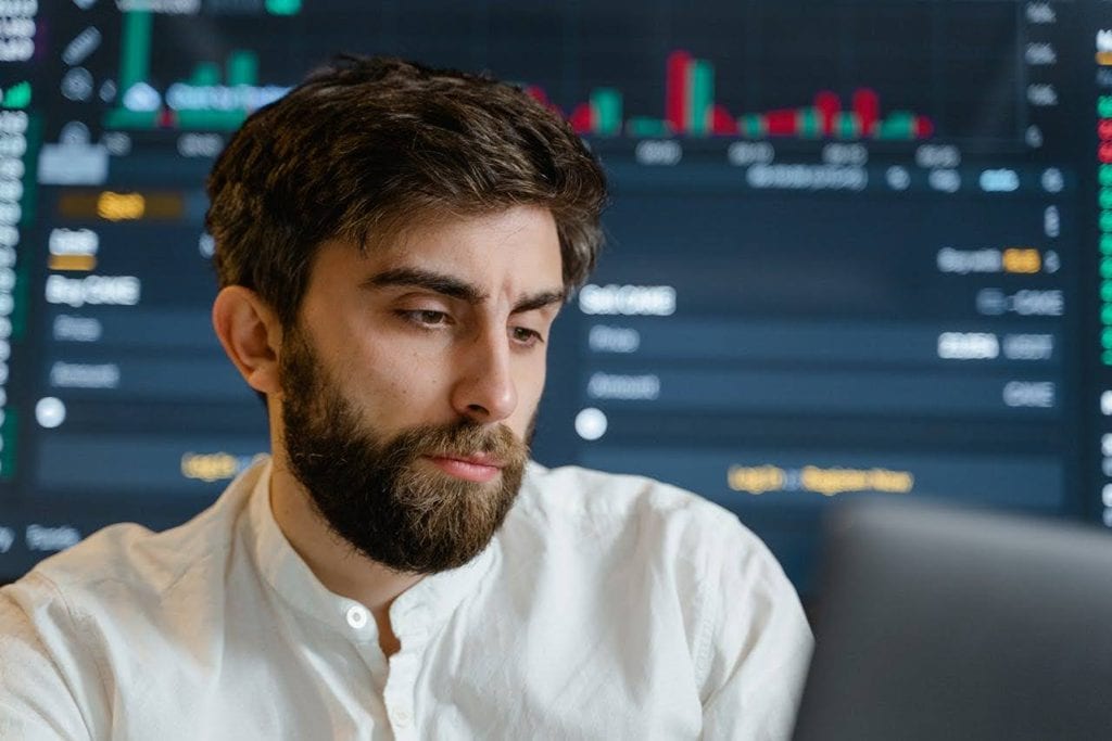 Focused man in white shirt with stock market background.
