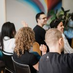 Group of people raising their hands during a presentation.