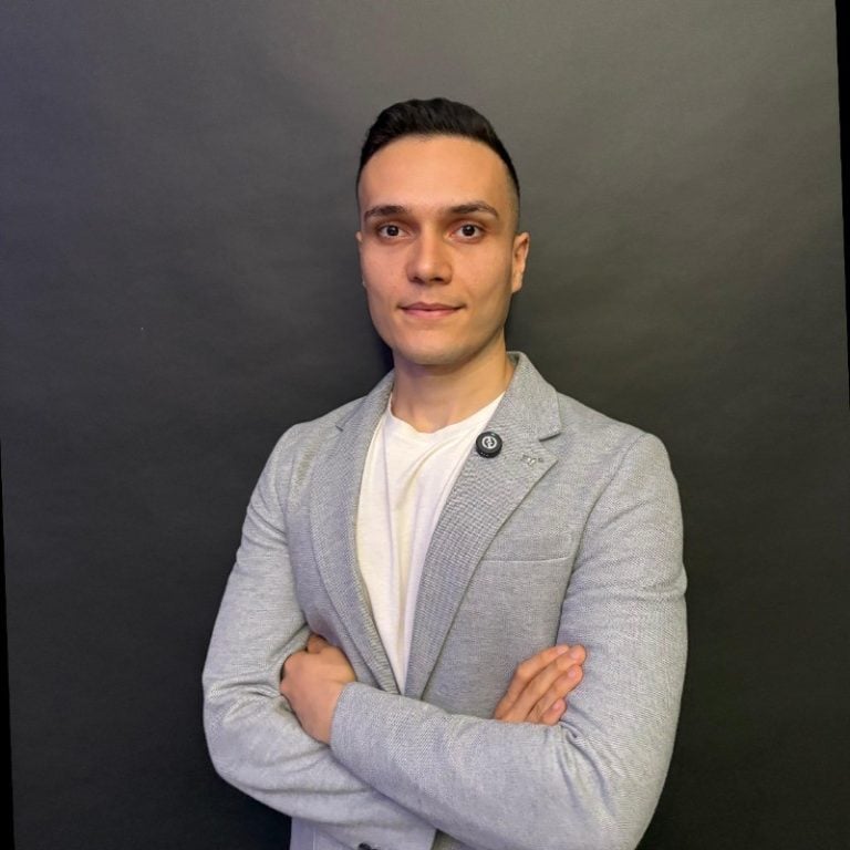 Professional headshot of a man in a grey blazer.