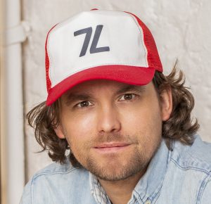 Man with brown hair wearing a red and white trucker hat.