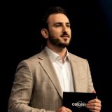 Man in a light blazer holding a Celonis branded folder.