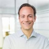 Smiling man in a light blue button-down shirt.